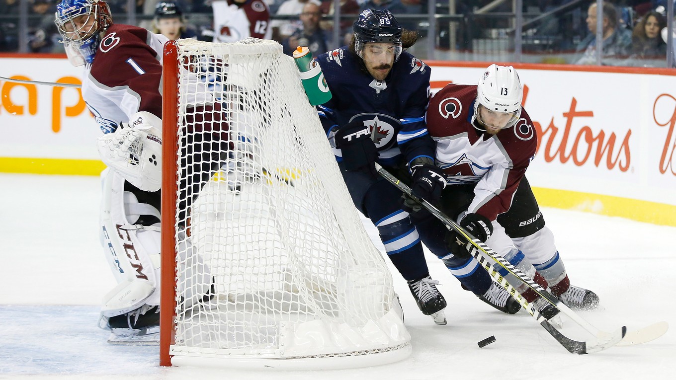 Mathieu Perreault (v strede) z Winnipegu obieha s pukom bránku bránený Alexandrom Kerfootom z Colorada.