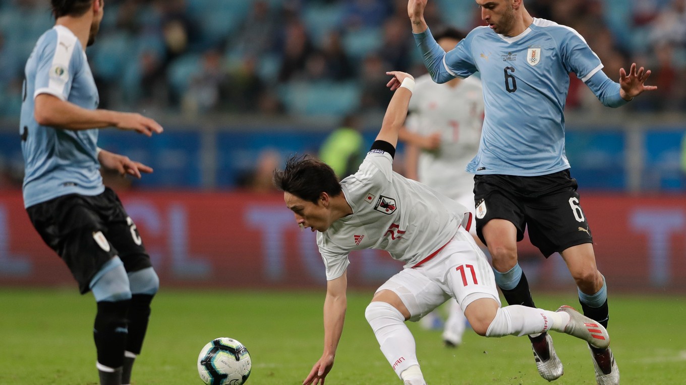 Kodži Mijoši v bielom drese Japonska strelil Uruguaju dva góly. Bráni ho Rodrigo Bentancur.