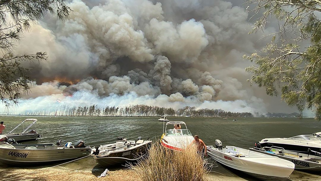 Člny sú priviazané na brehu jazera v malom meste Lake Conjola počas lesných požiarov v austrálskom štáte Nový Južný Wales.