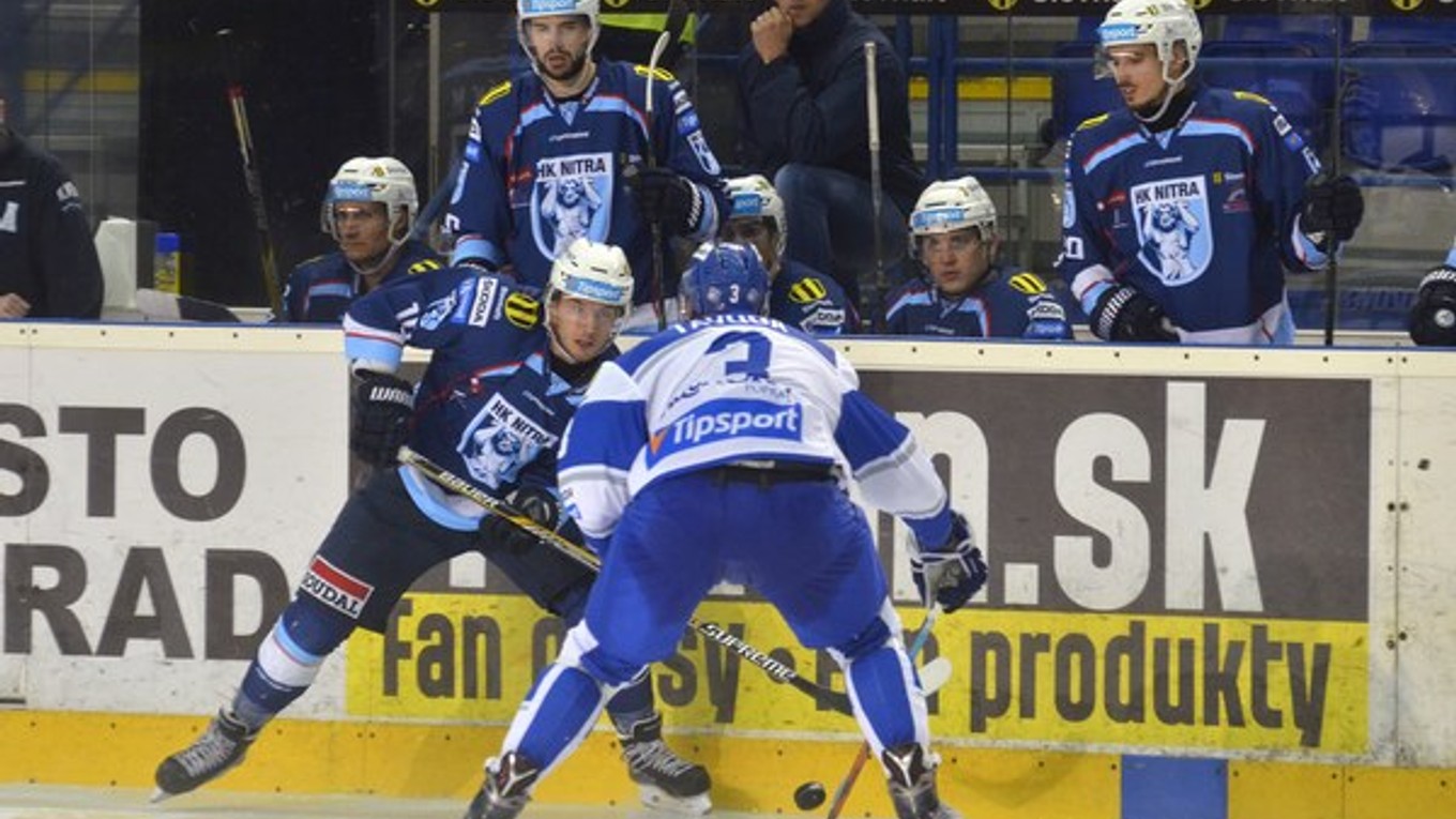 Hokejisti Nitry Filip Bajtek (na ľade vľavo) rozohráva puk pred hráčom Popradu Jánom Ťavodom.