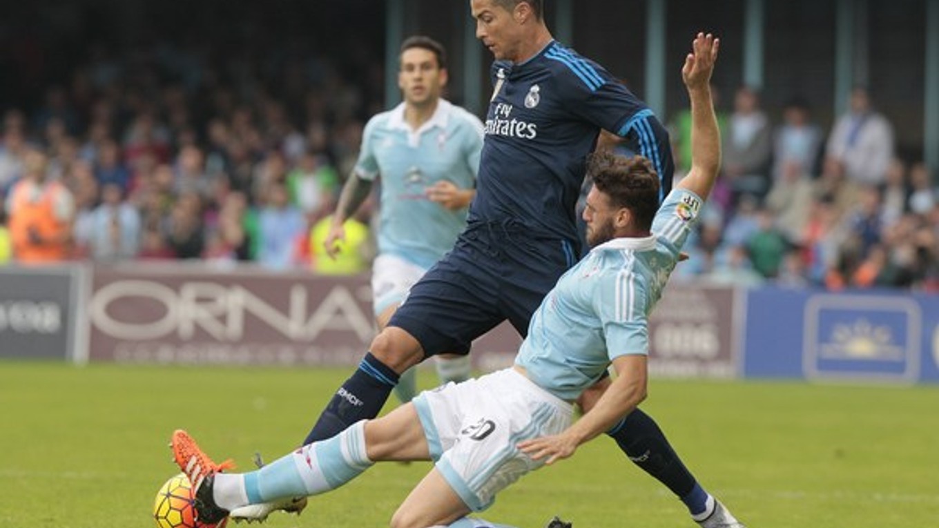 Sergio Gomez zo Celty Vigo (vpravo) sa sklzom pokúša vypichnúť loptu Cristianovi Ronaldovi.