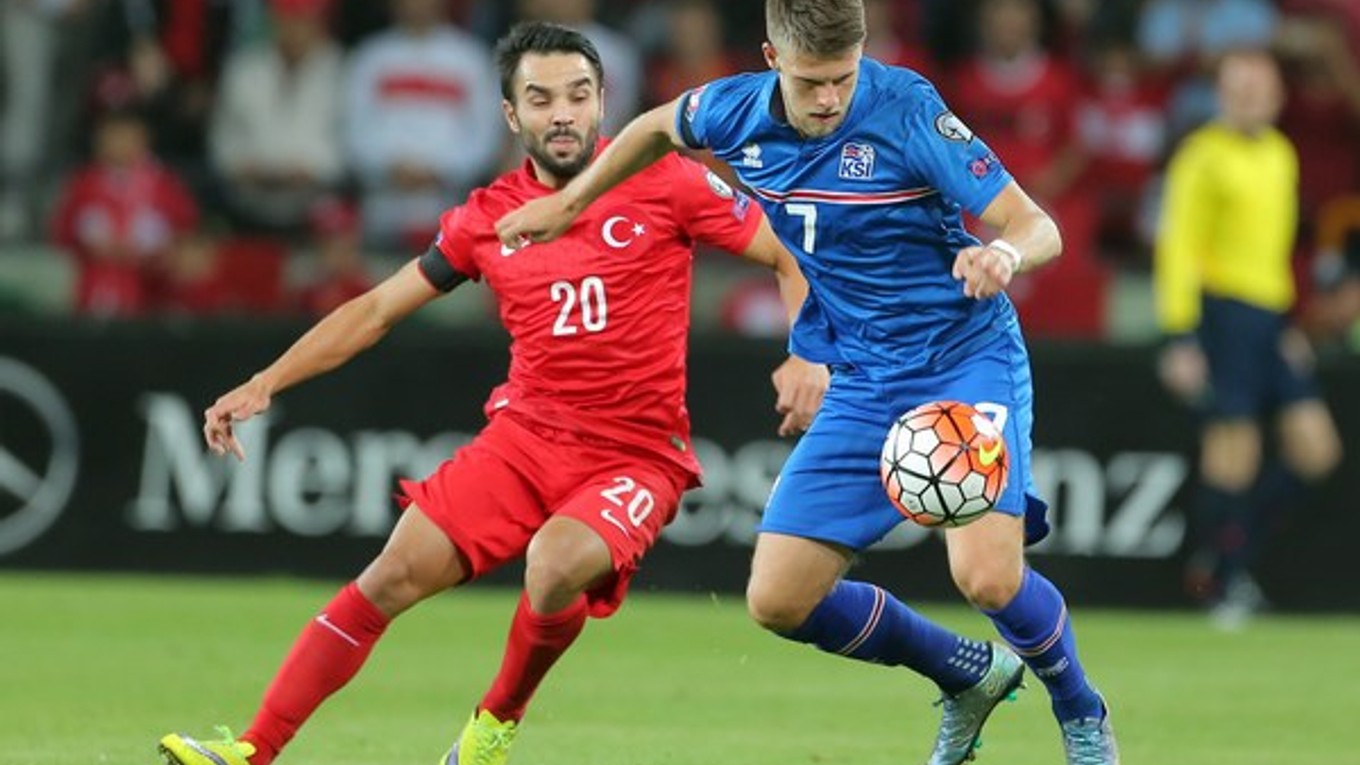 Ľavák Gudmundsson (č. 7) v súboji futbalovej kvalifikácie o EURO 2016 proti Turkovi Volkanovi Senovi.