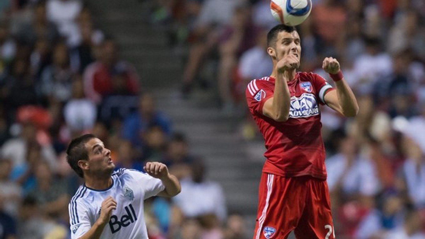 Octavio Rivero z tímu Vancouver Whitecaps sa prizerá, ako hlavičkuje loptu jeho súper Matt Hedges z Dallasu.