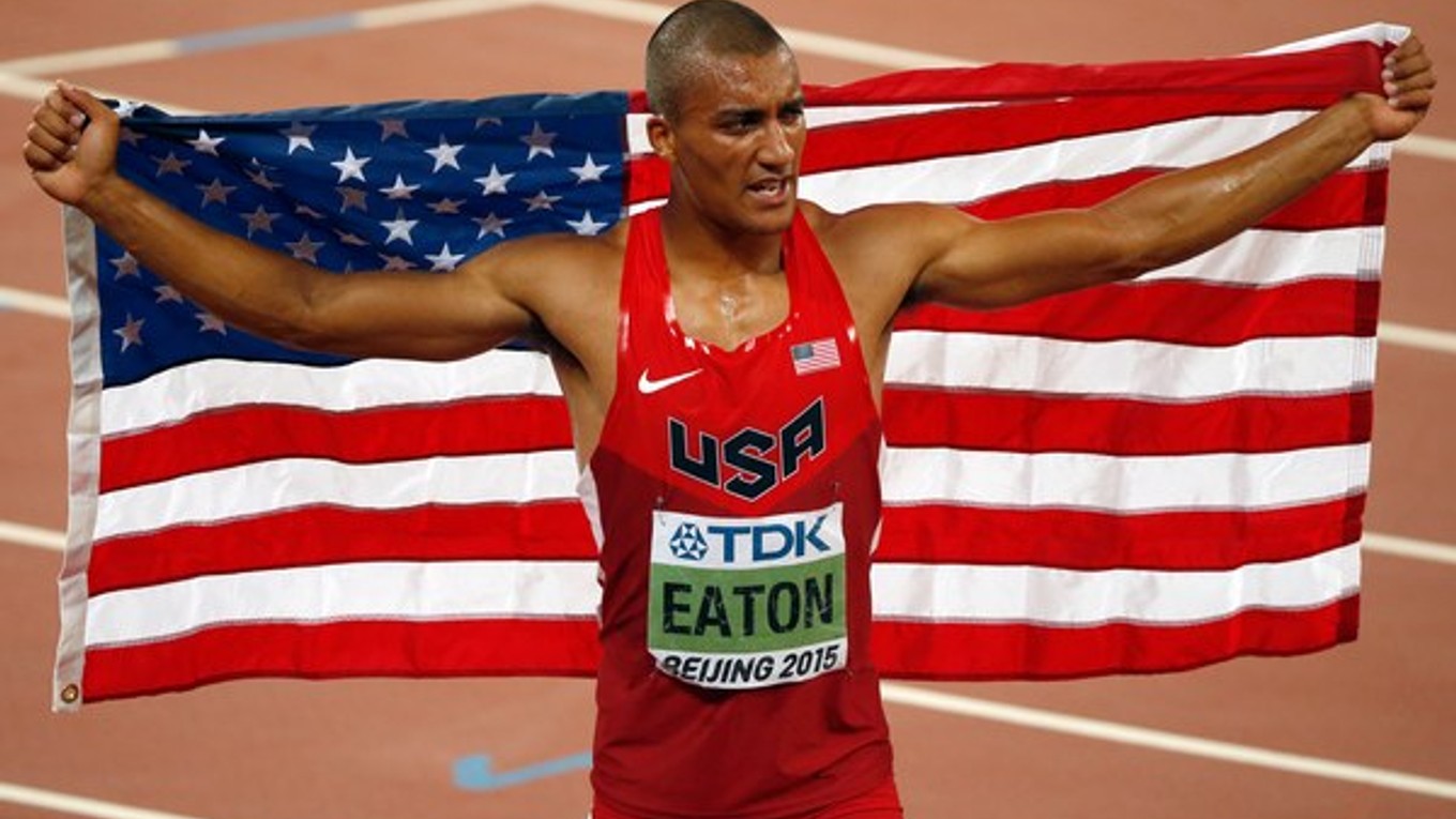 Vyčerpaný Ashton Eaton pózuje s národnou vlajkou.
