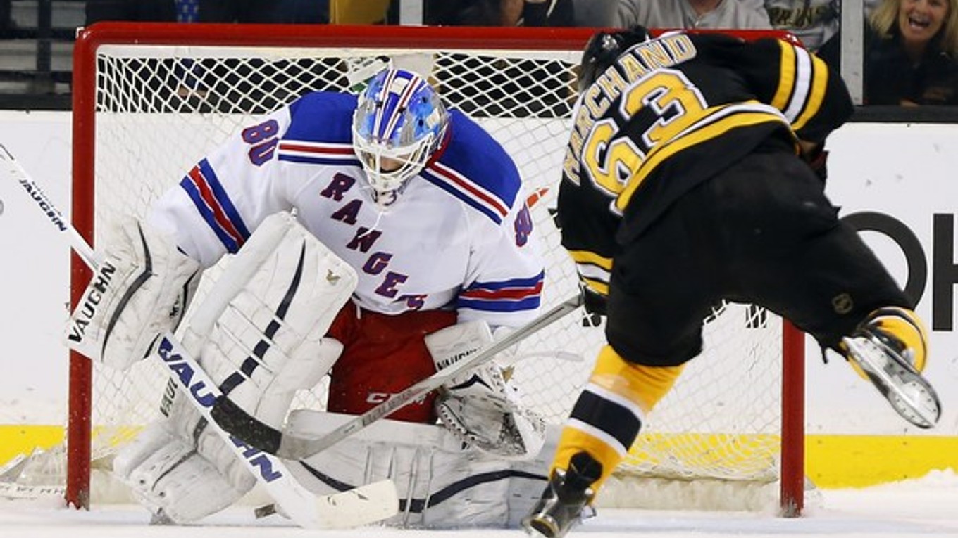 Hokejista Bostonu Bruins Brad Marchand skóruje pomedzi betóny brankára New Yorku Rangers Jeffa Malcolma.