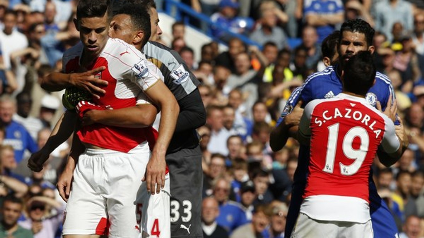 Hráča Arsenalu Gabriela (vľavo s číslom 5) a Diega Costu (vpravo v modrom drese) museli oddeľovať od seba spoluhráči po tom, ako futbalista Chelsea nešetrne zasiahol Laurenta Koscielneho do tváre.