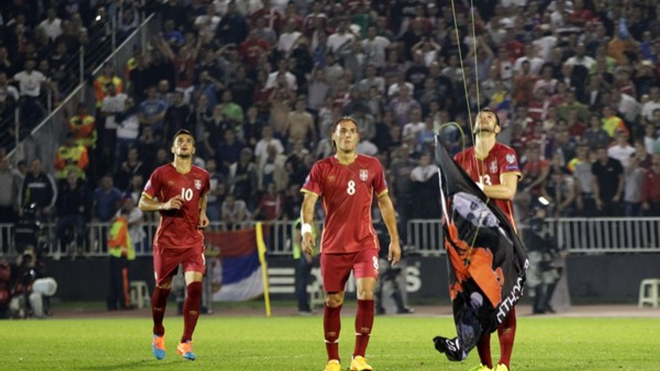 Srbský futbalista Stefan Mitrovič reaguje na provokáciu a strháva albánsku vlajku, ktorá lietala na minihelikoptére nad štadiónom. Následne sa na ihrisku strhla bitka.