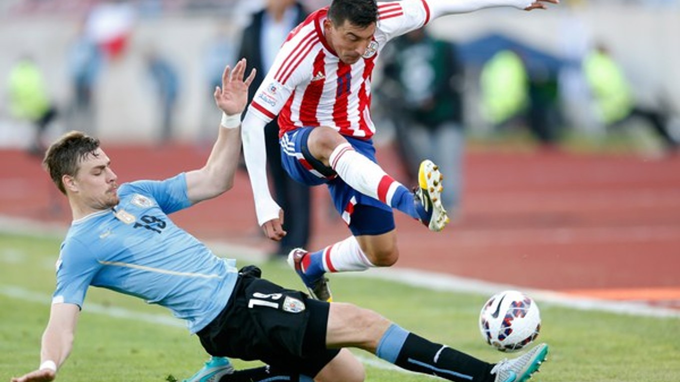 Uruguajčan Sebastian Coates (vľavo) sklzom vypichuje loptu Edgarovi Benitezovi z Paraguaja.