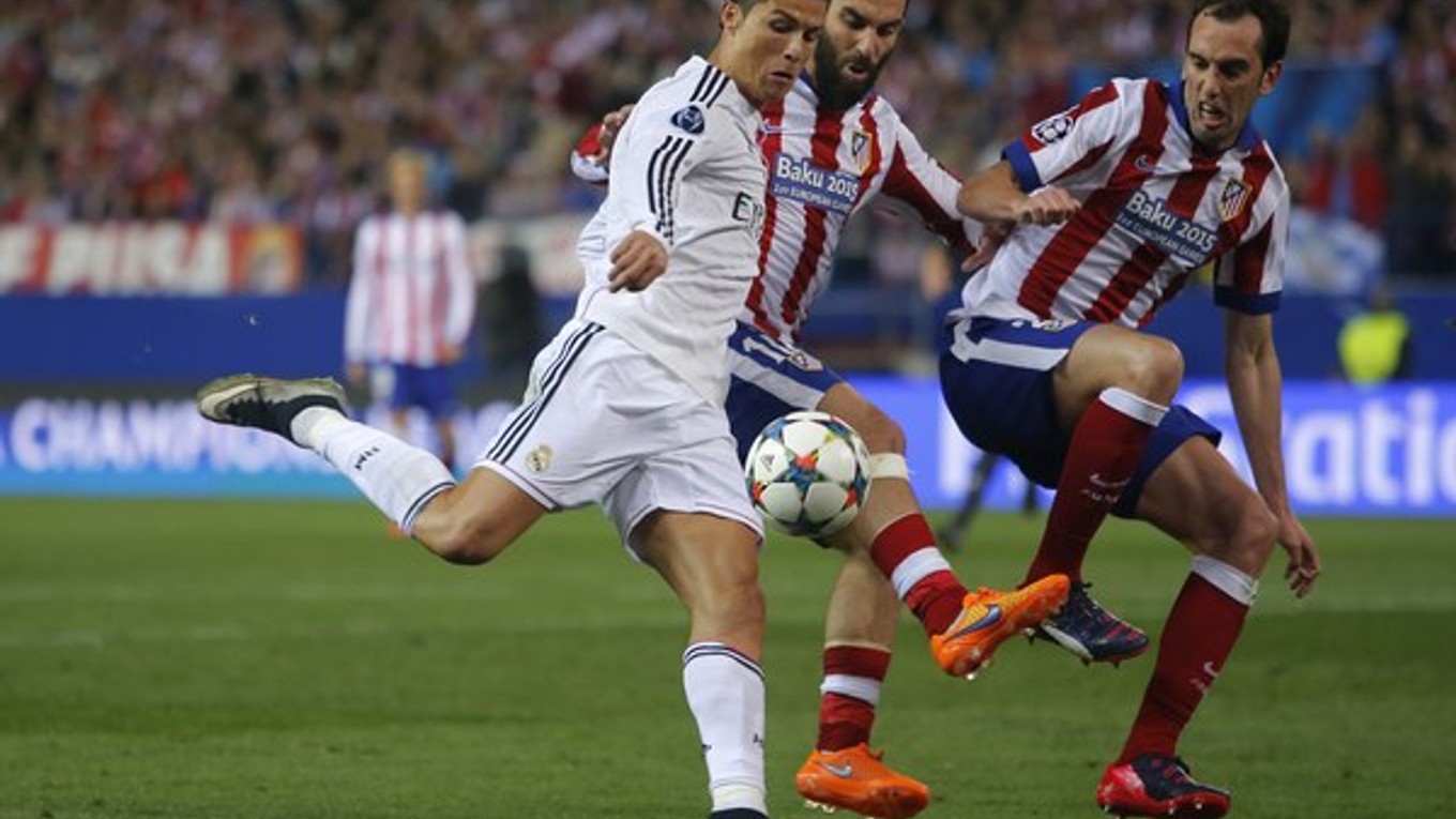 Cristiano Ronaldo (v bielom) sa dostáva do zakončenia. Zblokovať jeho pokus sa snaží dvojica hráčov Atlética - Diego Godín (vpravo) a Arda Turan.