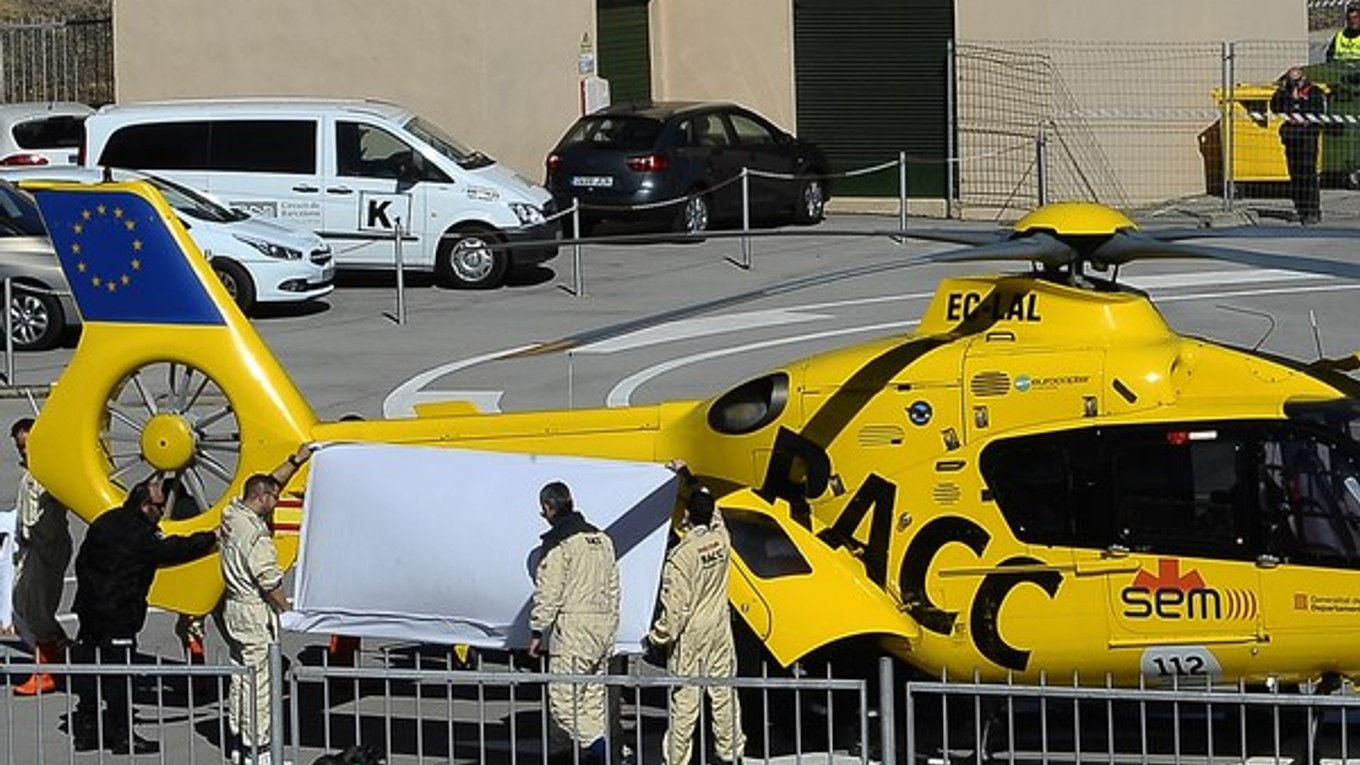 Zdravotný personál prenáša Fernanda Alonsa do helikoptéry po nehode v Barcelone.