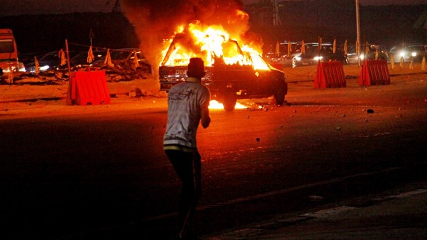 Horiace auto a zdevastované ulice po nepokojoch pred futbalovým zápasom.