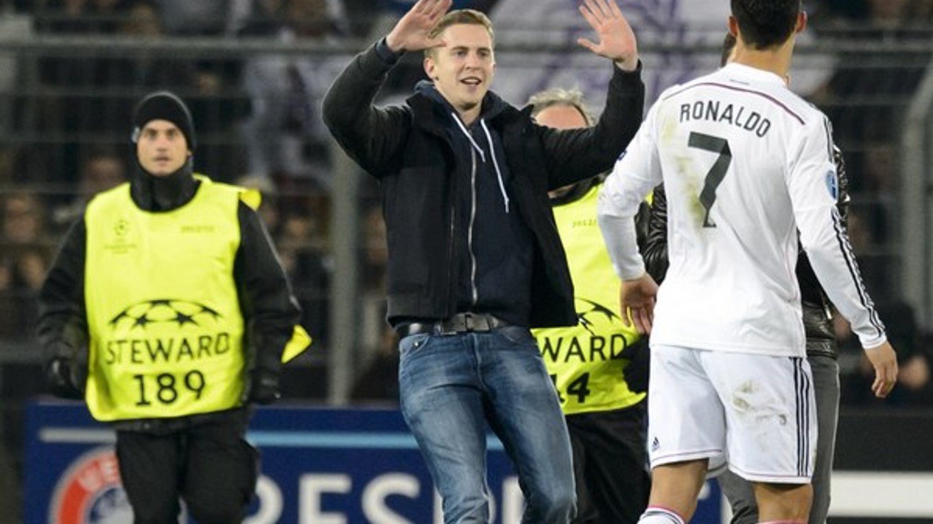Futbalový fanúšik, ktorý vbehol na trávnik, beží ku Cristianovi Ronaldovi počas zápasu Ligy majstrov FC Bazilej - Real Madrid 26. novembra.