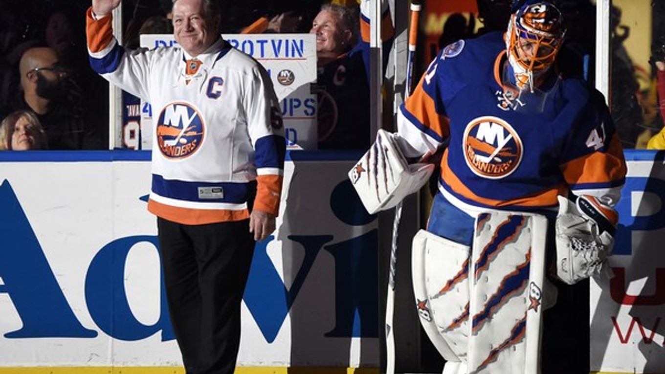 Bývalý hráč New Yorku Islanders Denis Potvin máva fanúšikom, vpravo vstupuje na ľad brankár Islanders Jaroslav Halák pred zápasom NHL proti New Jersey 29. novembra 2014 v Uniondale.