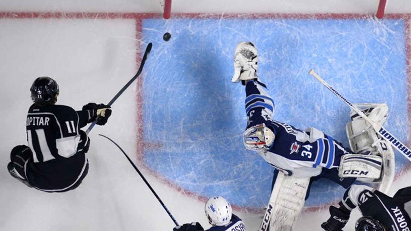 Center Los Angeles Kings Anže Kopitar (vľavo) strieľa gól brankárovi Michaelovi Hutchinsonovi z Winnipegu Jets, vpravo sa pozerá Marián Gáborík, 12. októbra.