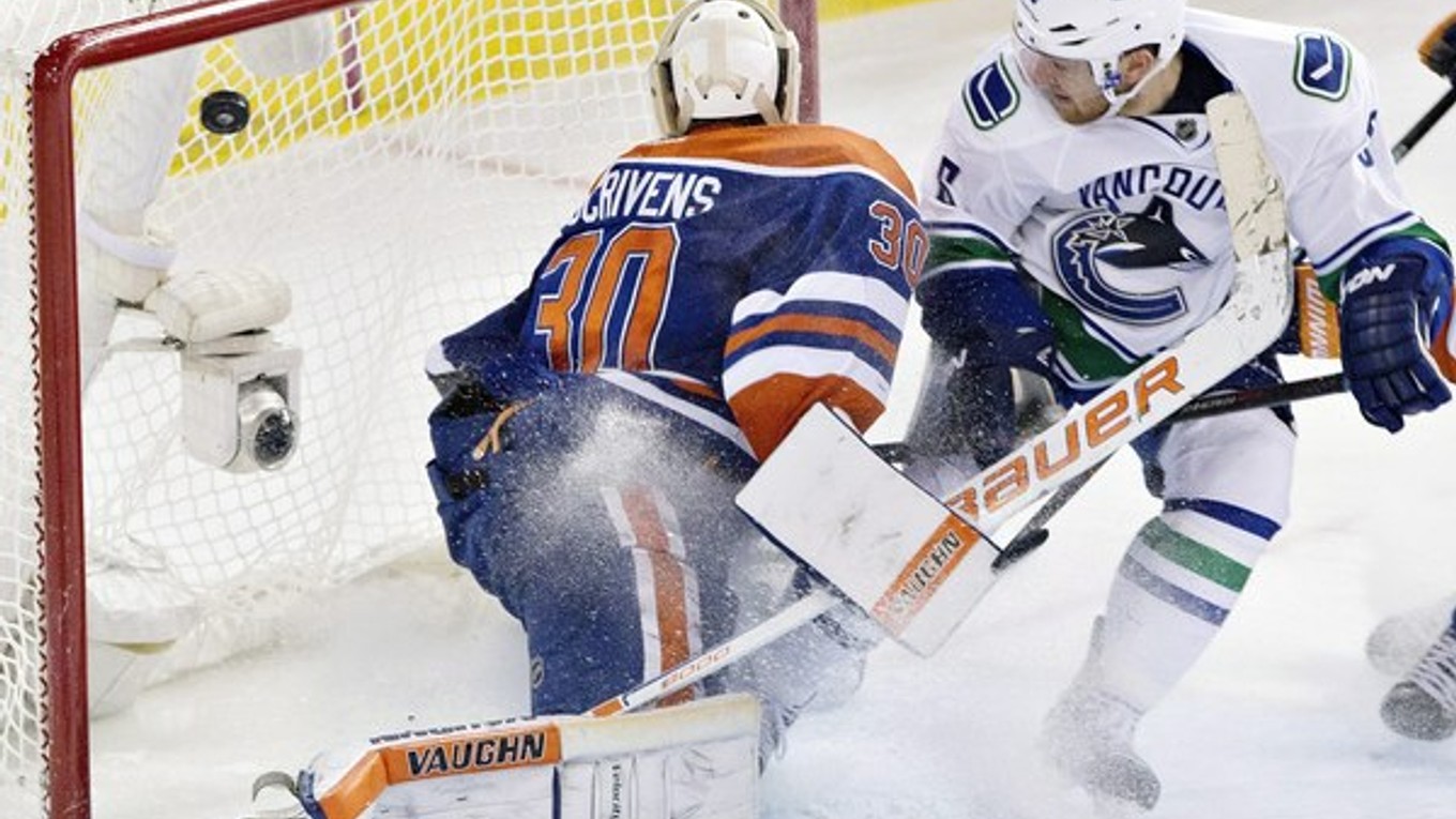 Yannick Weber z Vancouver Canucks dáva gól brankárovi Edmontonu Oilers Benovi Scrivensovi.