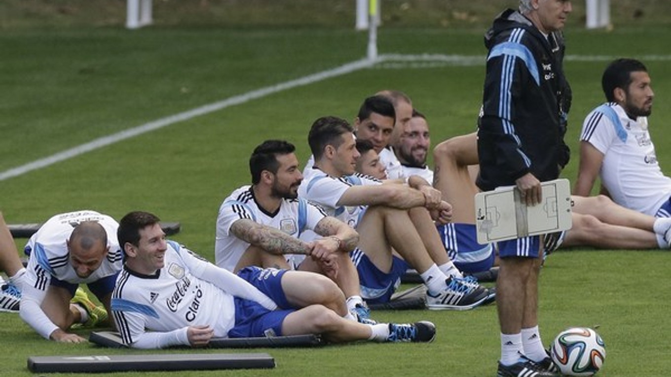 Argentínski futbalisti Javier Mascherano (vľavo) a Lionel Messi (druhý vľavo) sedia s ostatnými spoluhráčmi vedľa trénera Alejandra Sabellu počas tréningu.