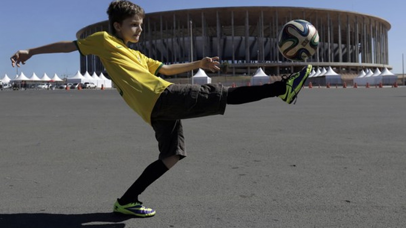 Chlapec sa hrá s loptou pred štadiónom v hlavnom meste Brasilia.