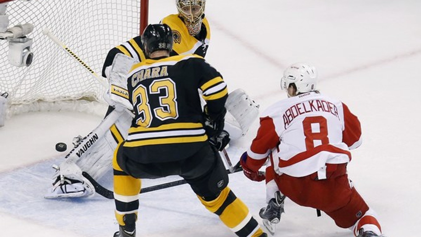 Brankár Bostonu Tuukka Rask zastavuje strelu hráča Detroitu Justina Abdelkadera, vľavo je Zdeno Chára.