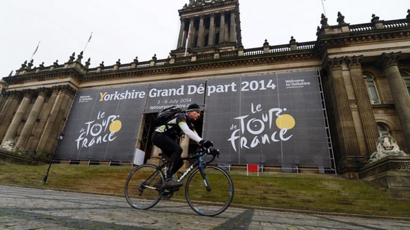 Cyklista prechádza okolo veľkého banneru k Tour 2014 na budove mestskej radnice v Leedsi.