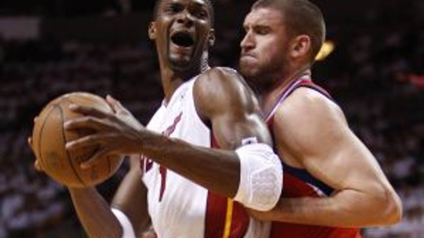 Hviezda Miami Heat Chris Bosh (v bielom) bránený Spencerom Hawesom (Philadelphia 76ers)