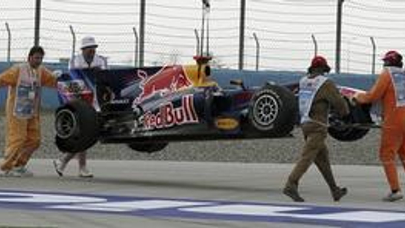 Organizátori odnášajú monopost Sebastiana Vettela.