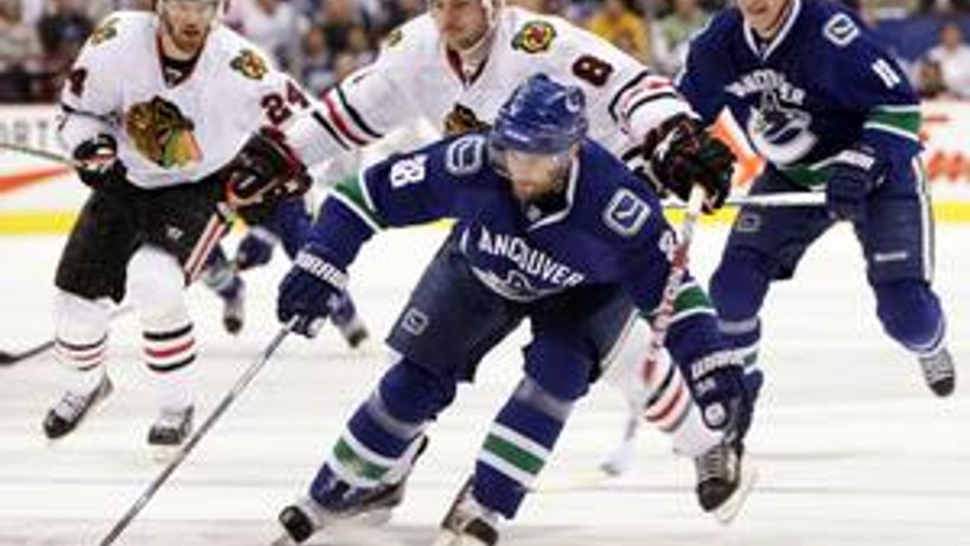 Pavol Demitra z Vancouveru (uprostred) uniká s pukom pred Mattom Walkerom z Chicago Blackhawks.