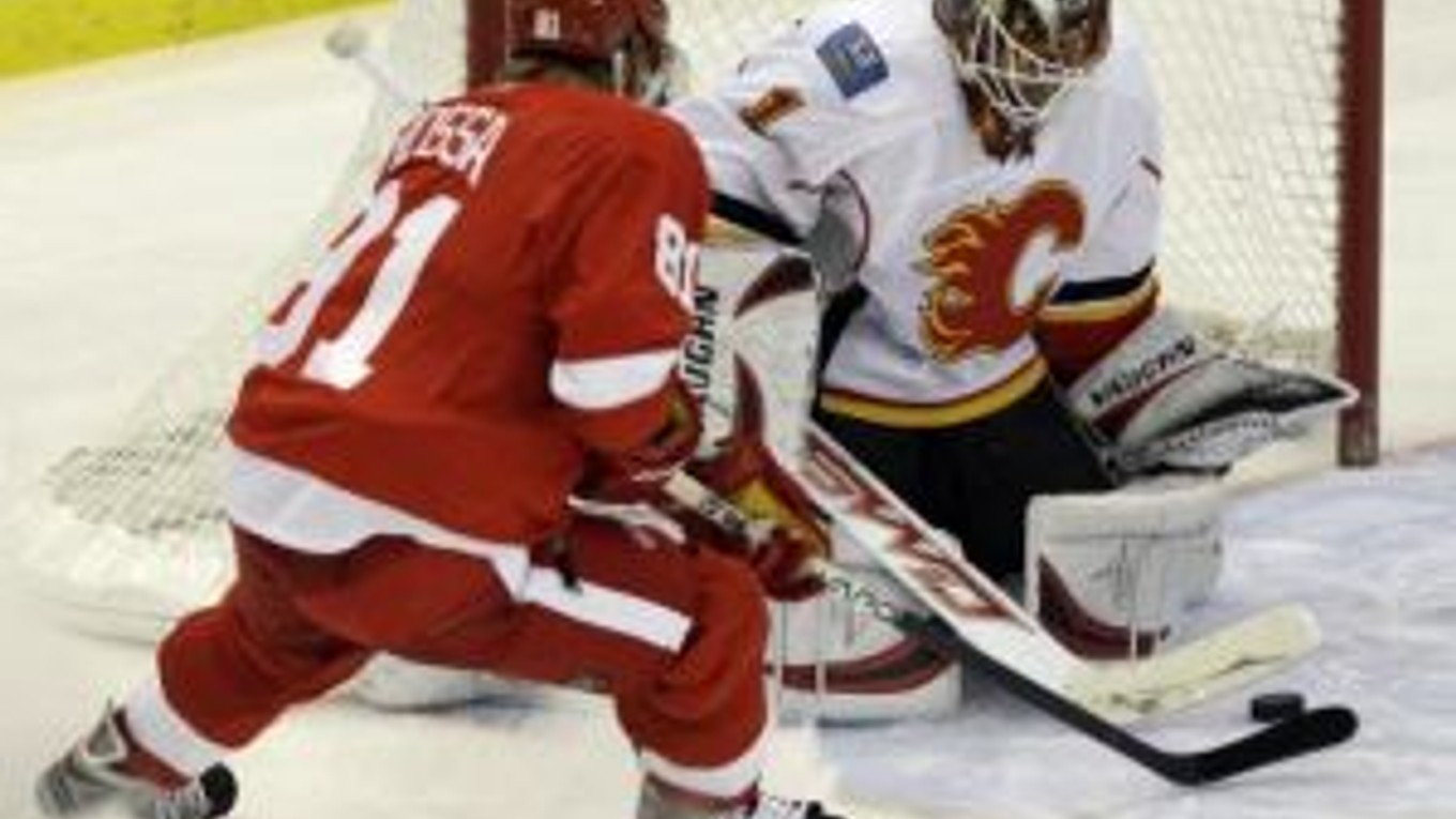 Brankár Calgary Flames Curtis McElhinney zasahuje pred Slovákom Marianom Hossom z Detroitu Red Wing.