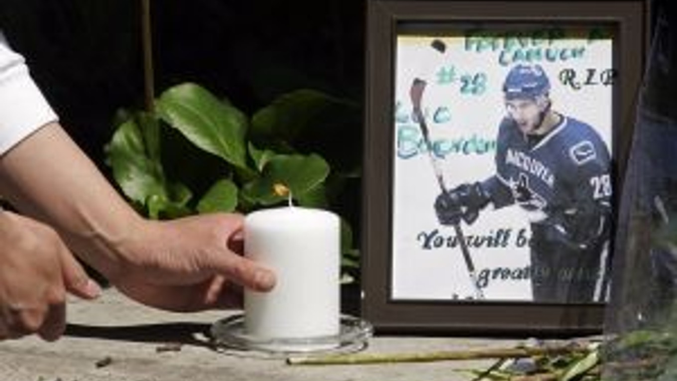 Fanúšik umiestňuje sviečku k fotografii zosnulého Luca Bourdona.