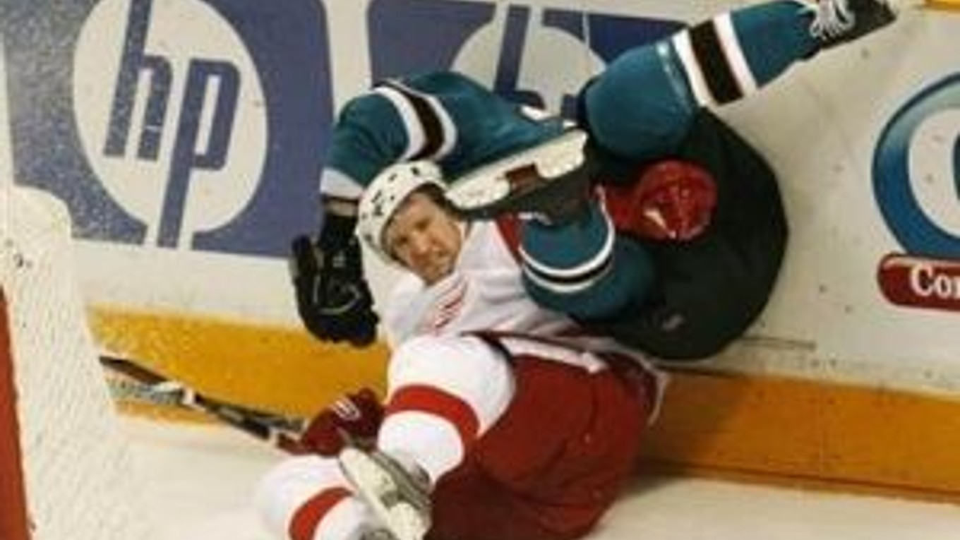 Ryan Clowe zo San Jose Sharks v tvrdom súboji s hráčom Detroitu Red Wings Niklasom Kronwallo, (v bielom).