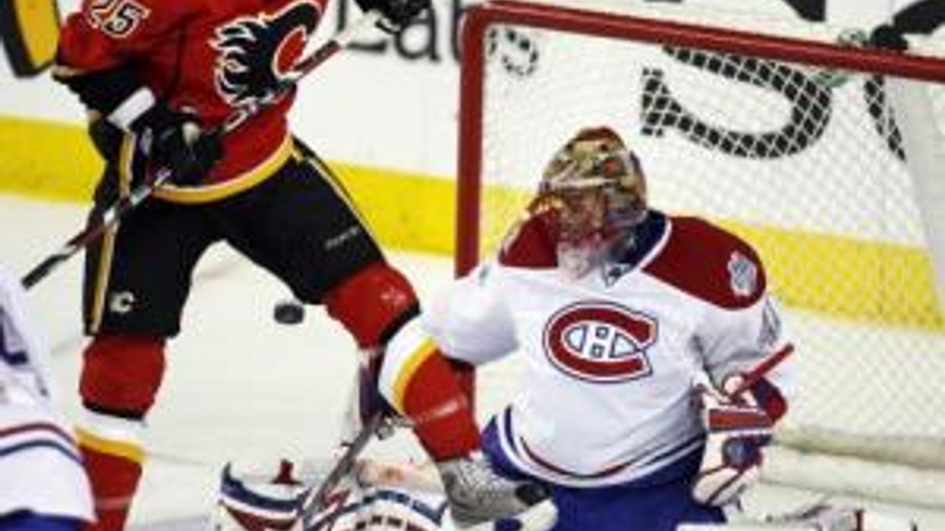 Slovenský brankár Montrealu Canadiens Jaroslav Halák chytá puk pred Davidom Mossom z Calgary Flames.