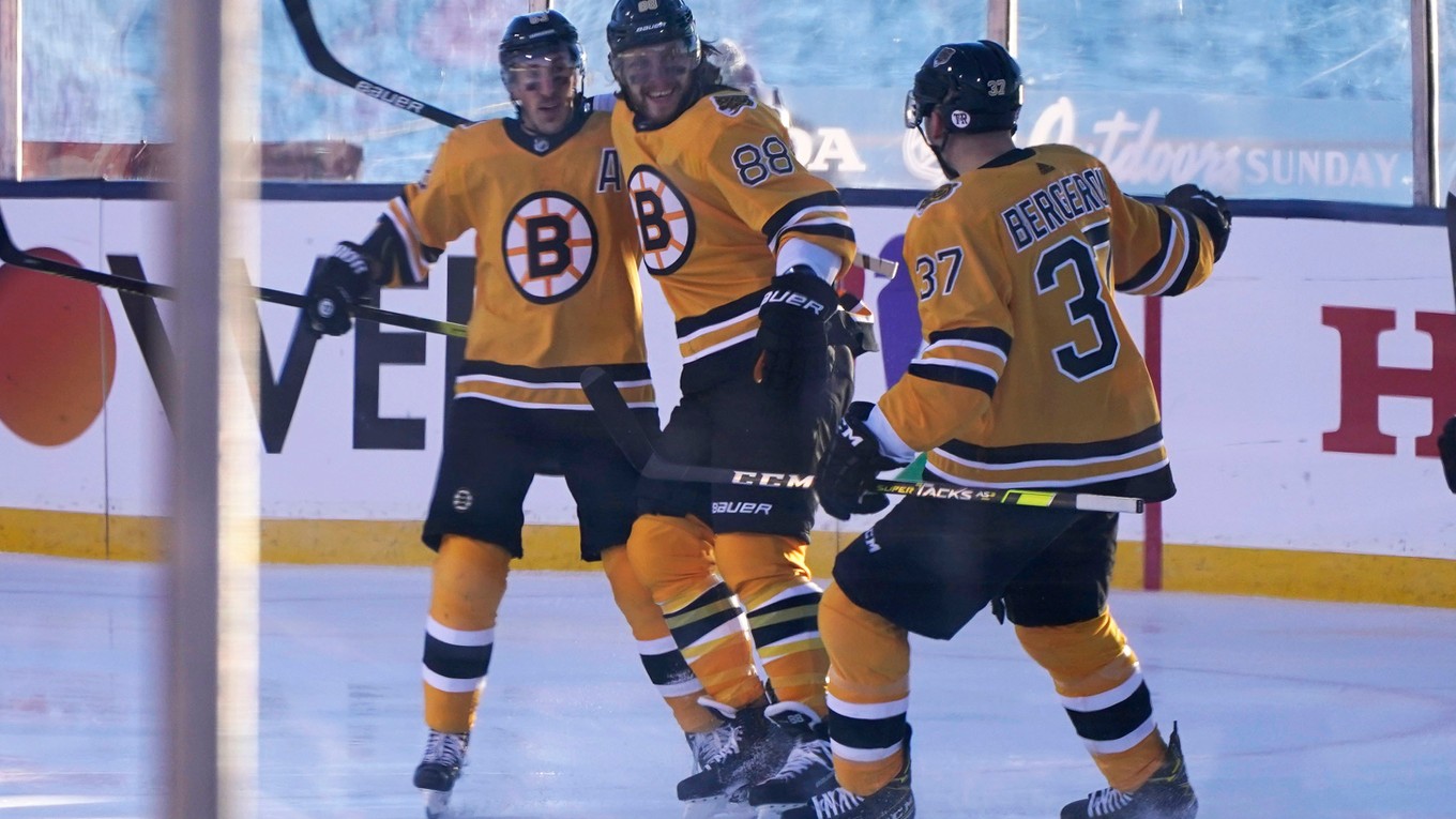 David Pastrňák, Brad Marchand a Patrice Bergeron sa tešia z gólu Bostonu Bruins pod holým nebom.
