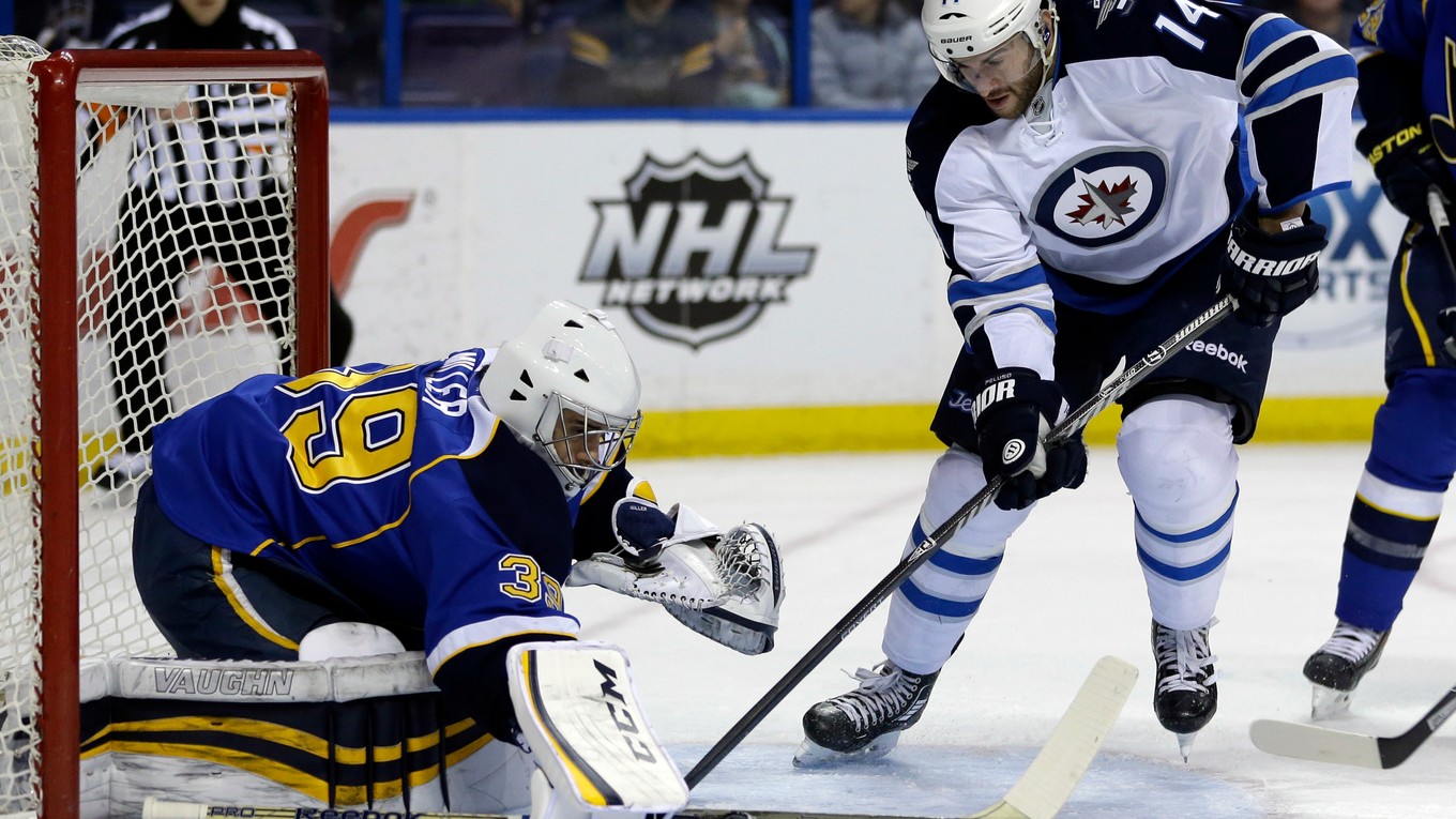 Anthony Peluso (vpravo) hral v NHL za Winnipeg, Washington a za Calgary. Na snímke v drese Jets proti brankárovi St. Louis Blues Ryanovi Millerovi.  