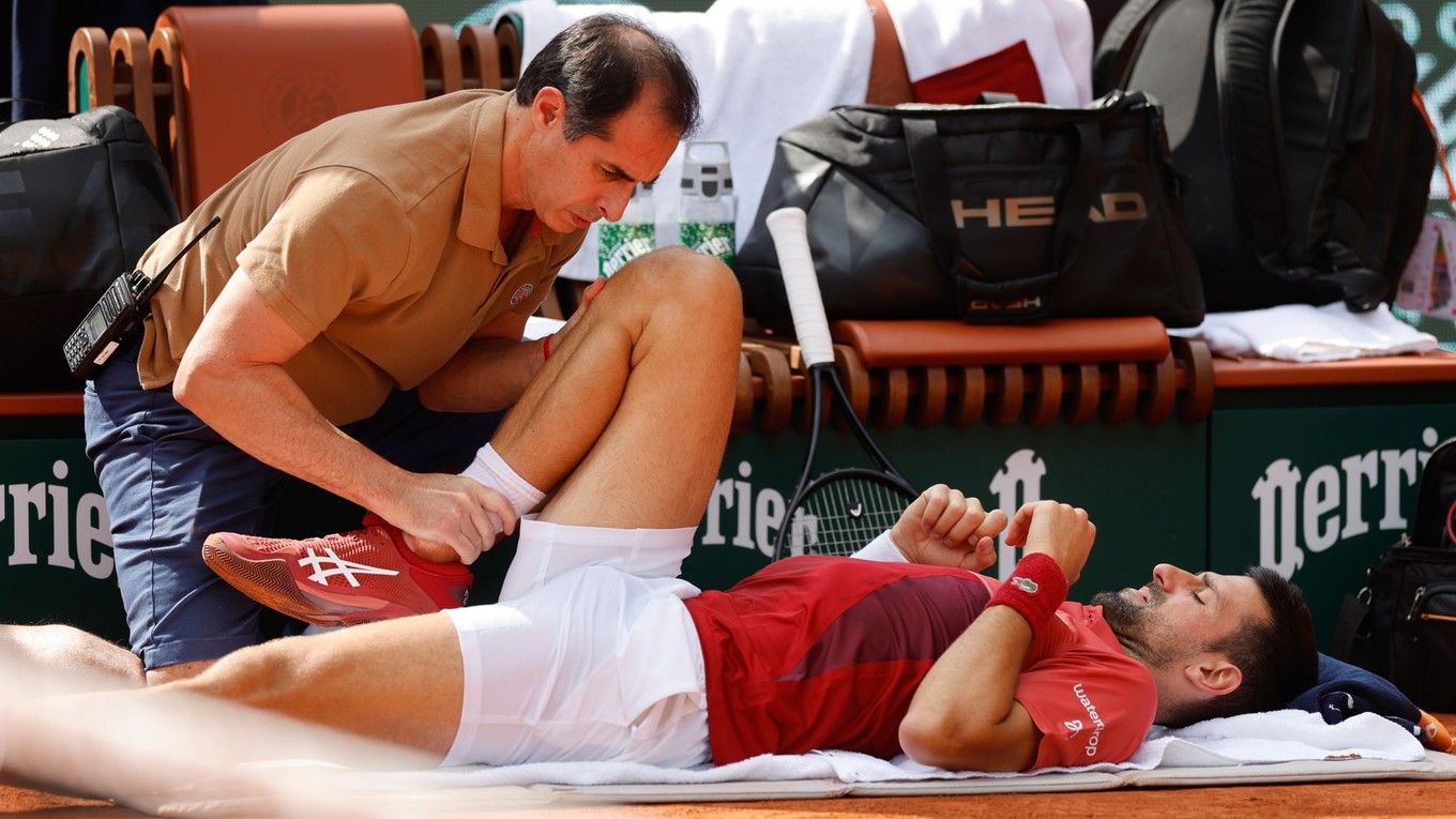 Novak Djokovič leží na kurte počas ošetrenia.