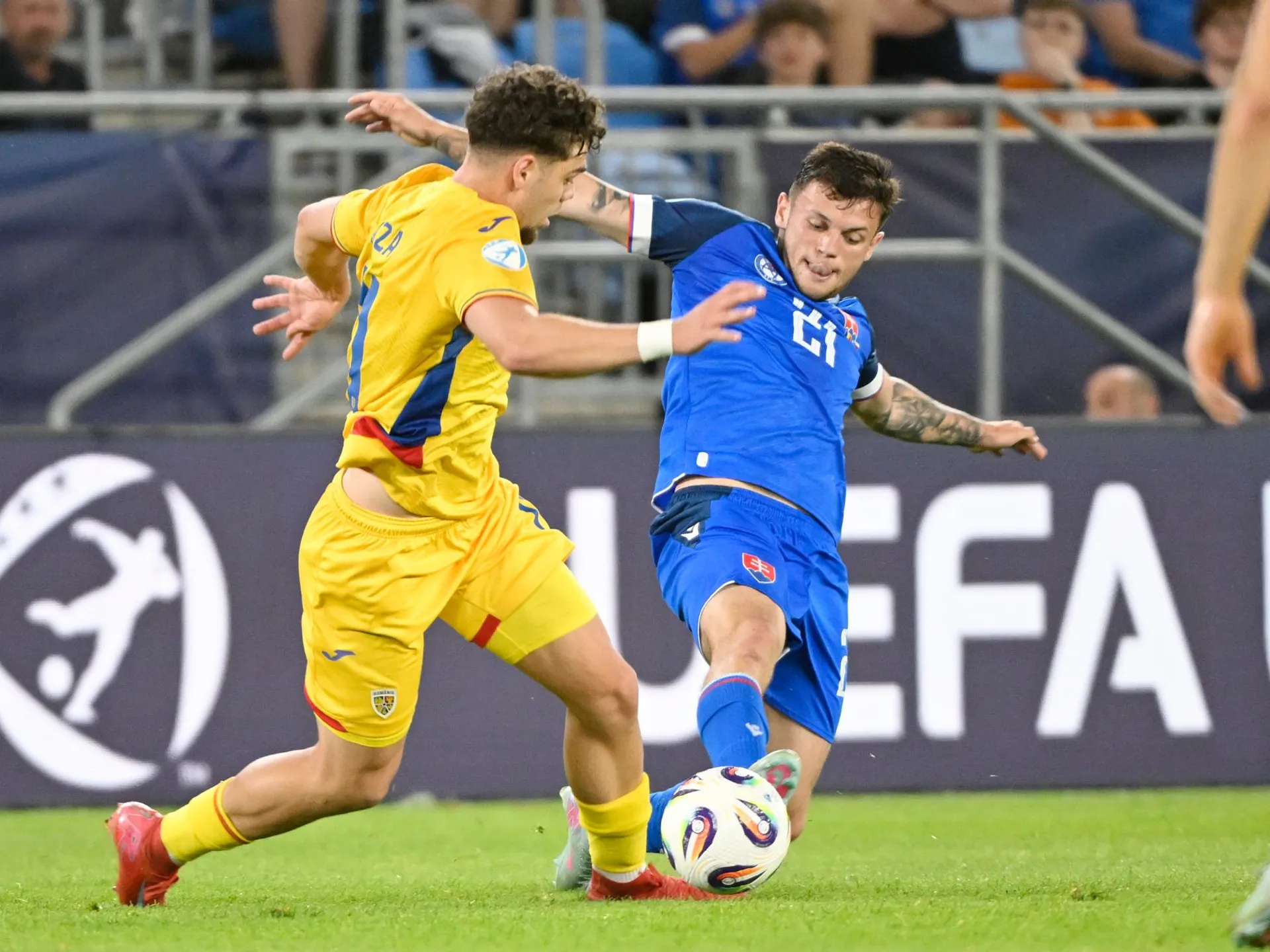 Na snímke sprava Samuel Kopásek (Slovensko) a  Sebastian-Andrei Borza (Rumunsko) bojujú o loptu počas zápasu základnej A-skupiny Rumunsko - Slovensko na majstrovstvách Európy futbalistov do 21 rokov v Bratislave v utorok 17. júna 2025.

