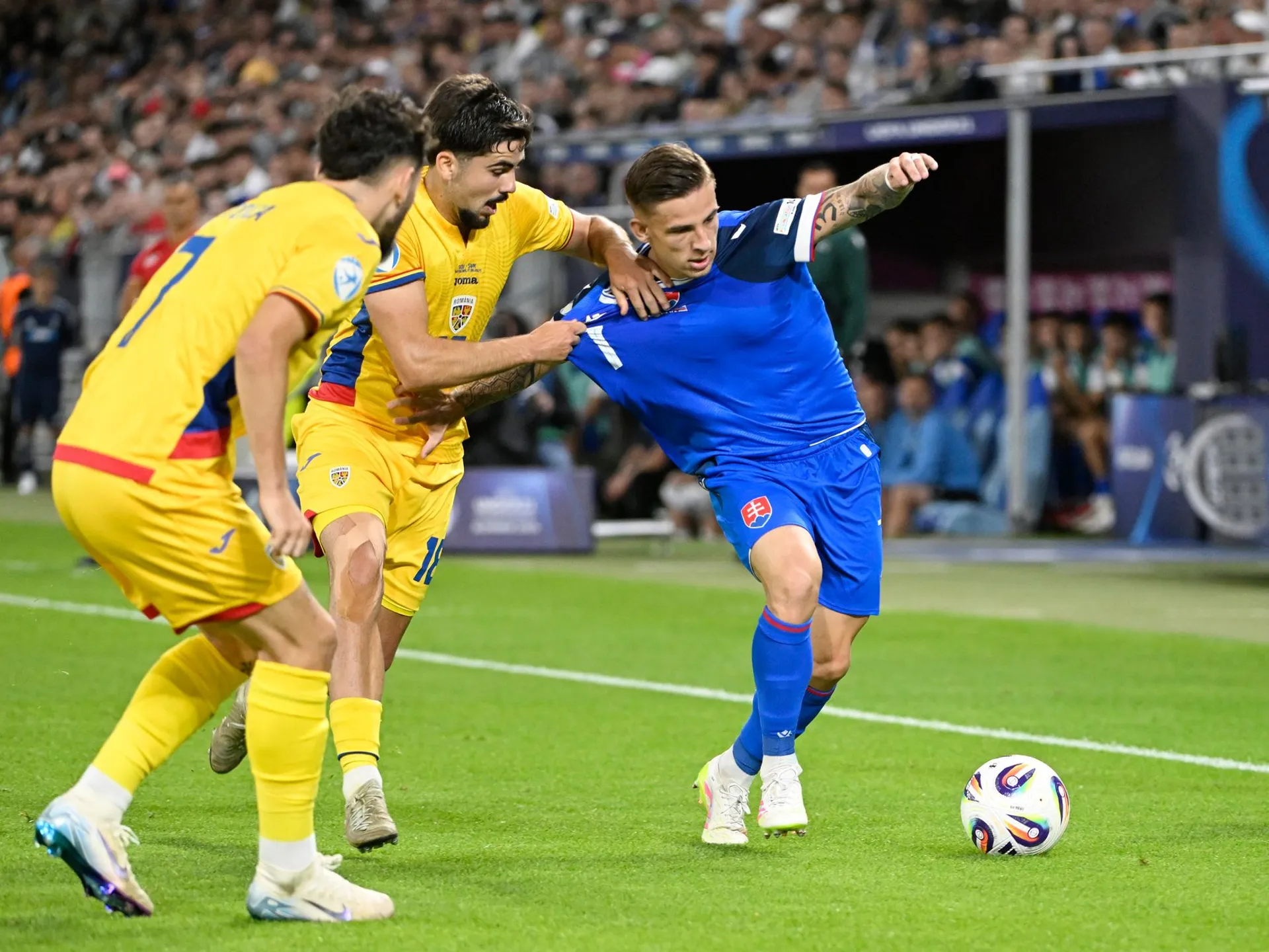 Na snímke sprava Tomáš Suslov (Slovensko), Tony-Joseph-Patrick Strata a Ianis Stoica (obaja Rumunsko) bojujú o loptu počas zápasu základnej A-skupiny Rumunsko -Slovensko.