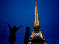 Nasvietená Eiffelova veža s olympijskými kruhmi večer pred slávnostným ceremoniálom na OH 2024.
