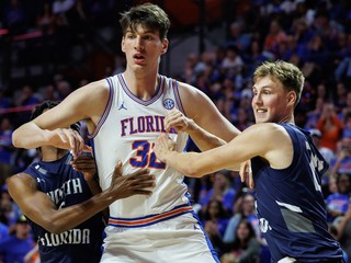 Na snímke basketbalista Floridy  Olivier Rioux (uprostred) a hráči Severnej Floridy  Dante Oliver (vľavo) a Nestor Dyachok (vpravo) počas zápasu univerzitnej basketbalovej ligy NCAA.