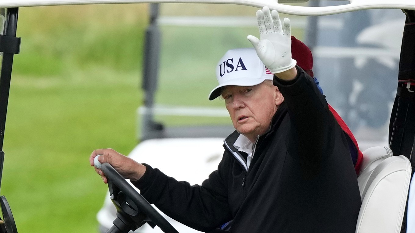 Donald Trump máva z golfového vozíka.