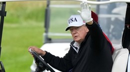 Donald Trump máva z golfového vozíka.