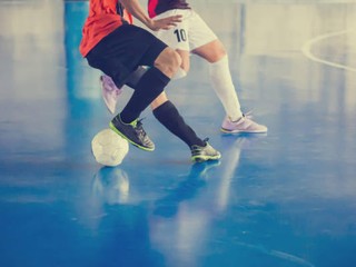 Indoor soccer sports hall. Football futsal player, ball, futsal floor. Sports background. Youth futsal league. Indoor football players with classic soccer ball.