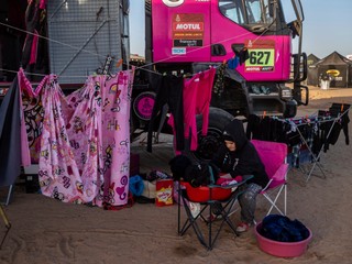 Žena perie a vešia prádlo vedľa kamióna počas voľného dňa na Rely Dakar. 