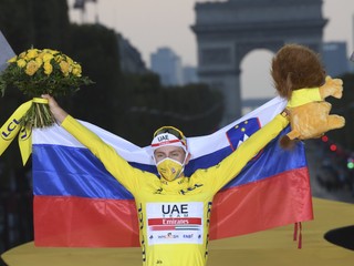 Tadej Pogačar pózuje v žltom drese a so slovinskou vlajkou.