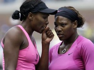 Americká tenistka Venus Williamsová (vľavo) si vymieňa pokyny so sestrou Serenou počas semifinále štvorhry žien proti ruskému páru Alise Klejbanovovej a Jekaterine Makarovej.
