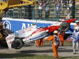 Usporiadatelia odnášajú havarovaný monopost Tima Glocka.