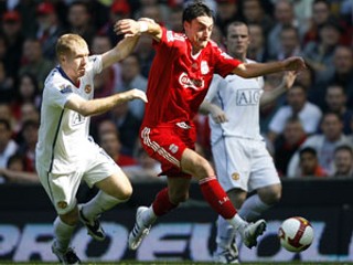 Albert Riera z Liverpoolu v súboji s Paulom Scholesom z Manchester United.