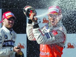 Víťaz Veľkej ceny Austrálie Lewis Hamilton z tímu McLaren oslavuje na stupni víťazov striekajúcim šampanským, vľavo je druhý v cieli Nick Heidfeld z BMW Sauber.