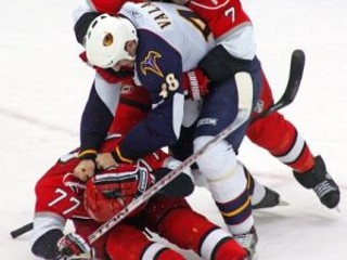 Niclas Wallin (7) z Caroliny oddeľuje slovenského obrancu Atlanty Borisa Valábika (48) od spoluhráča Joea Corva (77).