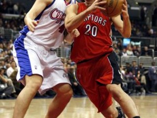Carlos Delfino z Toronta (v červenom) sa pokúša zakončiť cez hráča Los Angeles Clippers Paula Davisa.