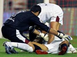 Situácie tesne po kolapse španielskeho reprezentanta  Antonia Puertu. Prvú pomoc mu dávajú brankár Sevilly Palop a Srb Dragutinovič.