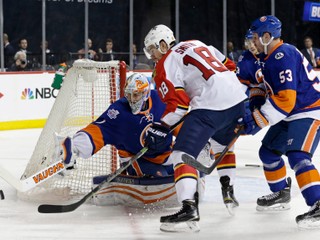 Reilly Smith z Floridy (č. 18) je natlačený pred gólmanov NY Islanders Thomasom Greisom.